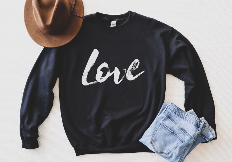 Puede incluir: Sudadera negra con la palabra "Love" escrita en letras blancas que parecen pintura.