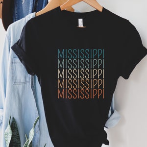 May include: Black t-shirt with the word "MISSISSIPPI" repeated six times in a gradient of teal, orange, and red.