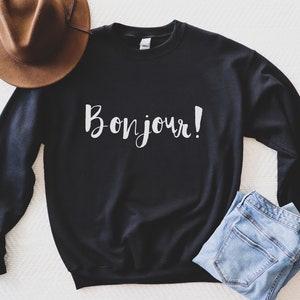 May include: Black sweatshirt with the text "Bonjour!" in white lettering.