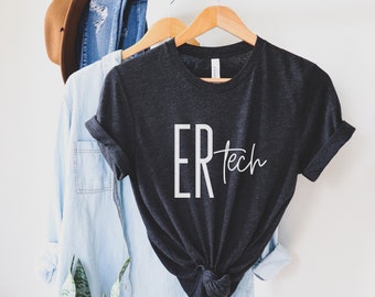 May include: A dark gray t-shirt with the text "ER Tech" in white lettering. The shirt is hanging on a wooden hanger.