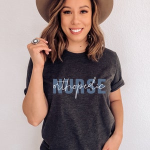 May include: A dark gray t-shirt with the text "NURSE orthopedic" in blue and white lettering.