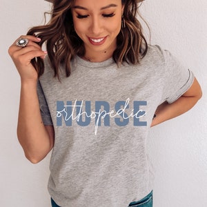 May include: A gray t-shirt with the text "orthopedic NURSE" in blue lettering. The text "orthopedic" is written in a cursive font.