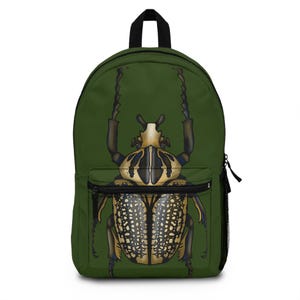 May include: Green backpack featuring a detailed illustration of a large beetle. The beetle has a tan and black pattern, with large antennae. The backpack has a front pocket, black zippers, and a black top handle.