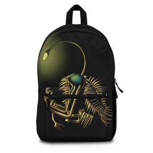 Pode incluir: Mochila preta com um design de criatura abissal bioluminescente. A ilustração apresenta um peixe-pescador amarelo e verde com uma isca brilhante e detalhes esqueléticos. Inclui um bolso frontal e um zíper preto.