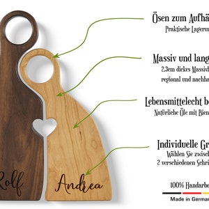 May include: Two wooden cutting boards, one brown and one light wood, are shaped like interlocking hearts. The boards have holes for hanging and are engraved with the names "Rolf" and "Andrea". The boards are made of 2.3 cm thick solid wood and are treated with food-safe oils and beeswax. They are 100% handmade in Germany.