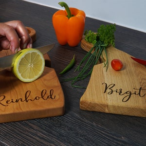 May include: Two personalized wooden cutting boards, one with the name "Reinhold" and the other with the name "Birgit".