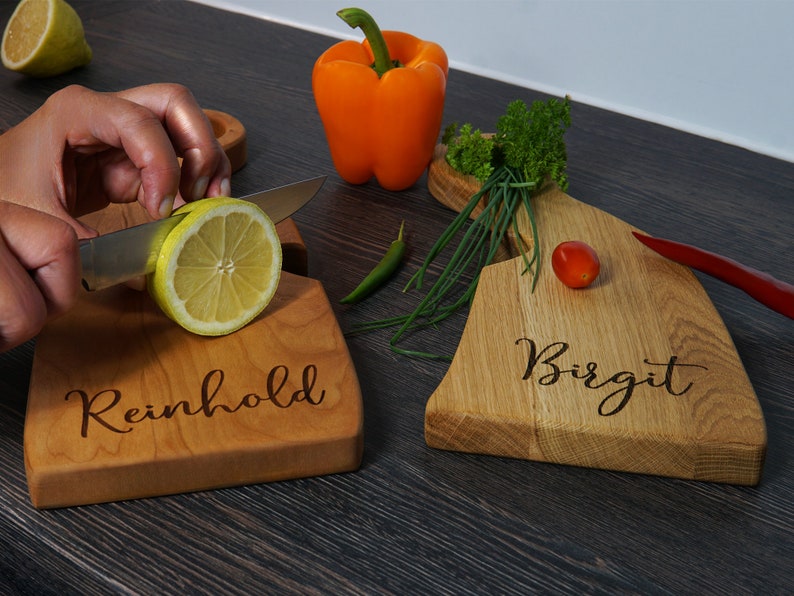 May include: Two personalized wooden cutting boards, one with the name "Reinhold" and the other with the name "Birgit".