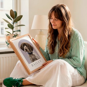 May include: A rectangular wooden frame containing a portrait print of a brown and white dog with a blue collar. The print features a purple arch background and the name BAILEY printed in black capital letters at the bottom of the white border.