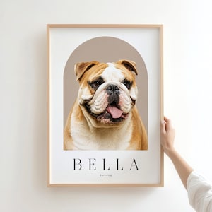 May include: A framed portrait print featuring a brown and white bulldog centered within a taupe arch graphic. Below the dog, the name BELLA is printed in black capital letters, followed by the word Bulldog in a smaller, simple font.