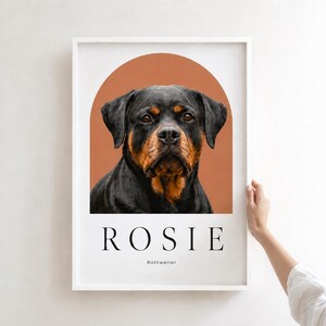 May include: A framed wall art print featuring a portrait of a black and tan Rottweiler dog centered within a terracotta-colored arch. Below the dog, the name ROSIE is printed in large black capital letters, with the word Rottweiler underneath.