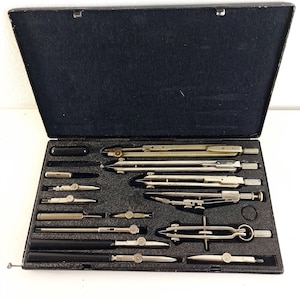 Può includere: Una valigetta da disegno vintage nera aperta, contenente vari compassi, divisori e altri strumenti da disegno argentati. L'interno è foderato in velluto nero e gli strumenti sono ordinatamente disposti. Gli strumenti variano per dimensioni e forma.