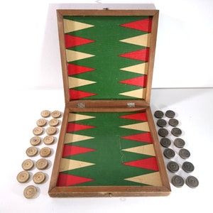 May include: A wooden backgammon game set with a green and red playing board, 15 black and 15 wooden playing pieces. The game is open and ready to play.