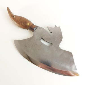 May include: A handcrafted, vintage-style cleaver with a polished steel blade and a wooden handle. The handle is a warm brown color, secured with brass rivets. The blade has a unique, decorative cutout near the handle.