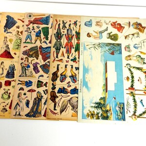 May include: A set of vintage paper dolls with colorful clothing and accessories. The dolls are dressed in various styles, including a sailor, a princess, and a soldier. The set includes a boat, a tree, and other props for creating scenes.