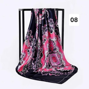 May include: A square silk scarf with a black border and a vibrant pink and black paisley design. The scarf is draped over a black metal stand, with the number "08" in a white box in the corner.