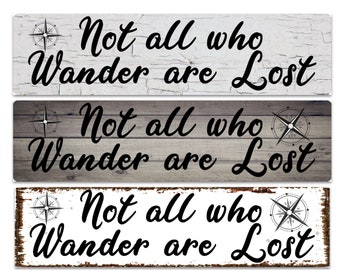 May include: Three rustic wooden signs with a distressed white, gray, and brown finish. Each sign features a compass design and the text "Not all who Wander are Lost".