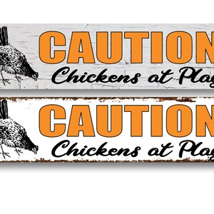 May include: Two white wooden signs with distressed paint and black chicken silhouettes. The signs read "CAUTION Chickens at Play" in orange letters.