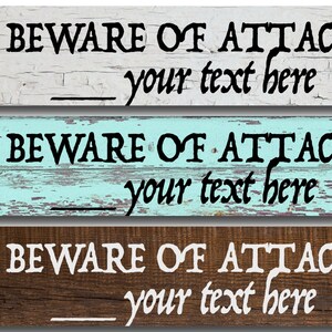 May include: Three wooden signs with distressed paint. Each sign reads "BEWARE OF ATTACK" with a blank space for personalized text. The signs are in white, light blue, and brown.