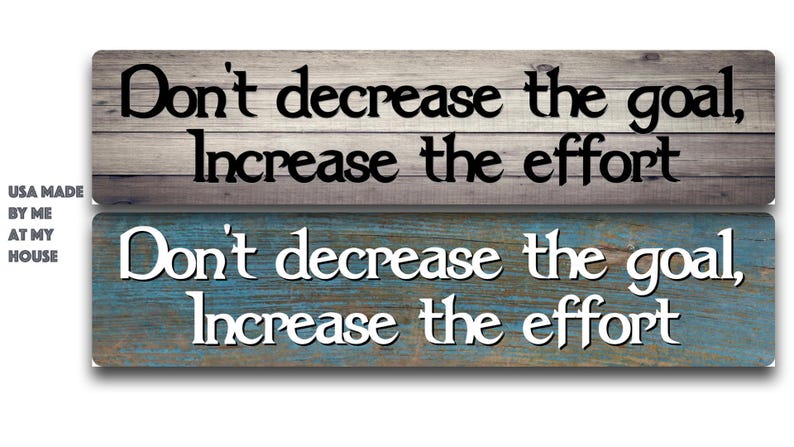 May include: Two rectangular wooden signs with motivational quotes. The top sign has a gray and brown wood grain background with black text that reads "Don't decrease the goal, Increase the effort." The bottom sign has a blue and brown wood grain background with white text.