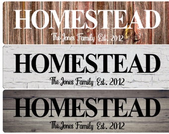 May include: Three variations of a wooden sign with the word "HOMESTEAD" in black or white lettering. The text "The Jones Family Est. 2012" is below the word "HOMESTEAD".