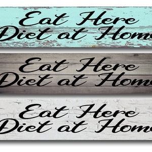 May include: Three wooden signs with a distressed paint finish. Each sign reads "Eat Here Diet at Home" in black cursive lettering.