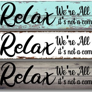 May include: Three wooden signs with a distressed, weathered look. Each sign features the text "Relax We're All Crazy it's not a competition" in black lettering.