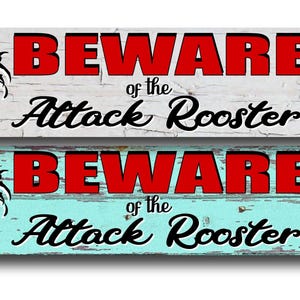 May include: Rectangular wooden sign with the text "BEWARE of the Attack Rooster" in red and black. The sign features a rooster illustration on each end. The background is distressed white and turquoise.