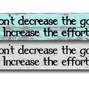 May include: Two wooden signs with the text "Don't decrease the goal, Increase the effort" in black. One sign is light blue, the other is white. The signs are made in the USA.