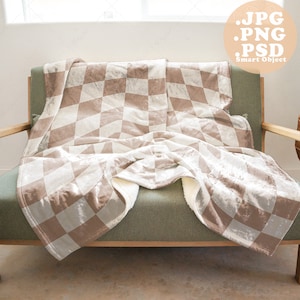 May include: A light brown and white checkered throw blanket draped over a green upholstered armchair. The blanket has a soft, plush texture.