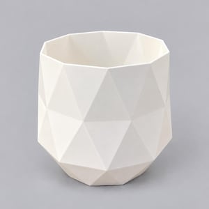 May include: A matte white ceramic planter featuring a faceted geometric exterior with a series of triangular panels. The vessel has an open top and a wide, angular body that tapers toward a smaller, flat base, creating a structured form.