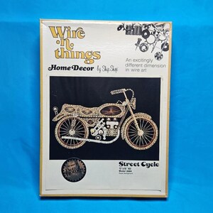 May include: A vintage "Wire 'n Things" home decor kit featuring a wire art motorcycle design. The kit includes a black background and is labeled "Street Cycle." The box has a cream and gold color scheme with the text "Better Homes."
