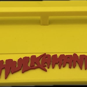 May include: Yellow plastic skateboard ramp with a red "Hulkamania" logo.