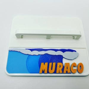 May include: White plastic nameplate with a blue and white wave design and the name "MURACO" in orange letters.