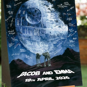 Könnte beinhalten: Eine Star Wars-Hochzeitstafel mit dem Todesstern, AT-AT-Läufern und einem Sternenhimmel. Auf dem Schild stehen die Namen "Jacob und Emma" und das Datum "18. April 2026". Unterschriften sind um den Todesstern geschrieben.