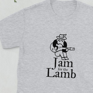 May include: A gray t-shirt with a black graphic of a person playing a guitar. The text "Jam for the Lamb" is printed below the graphic.