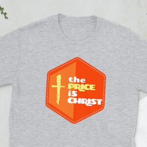 Peut inclure: T-shirt gris avec un graphique hexagonal orange et jaune qui dit "the price is christ" avec une croix &agrave; l'int&eacute;rieur de l'hexagone.