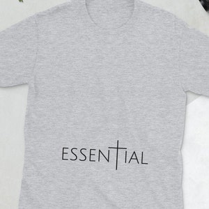 May include: A heather grey t-shirt with a black cross and the word "ESSENTIAL" printed on the front.