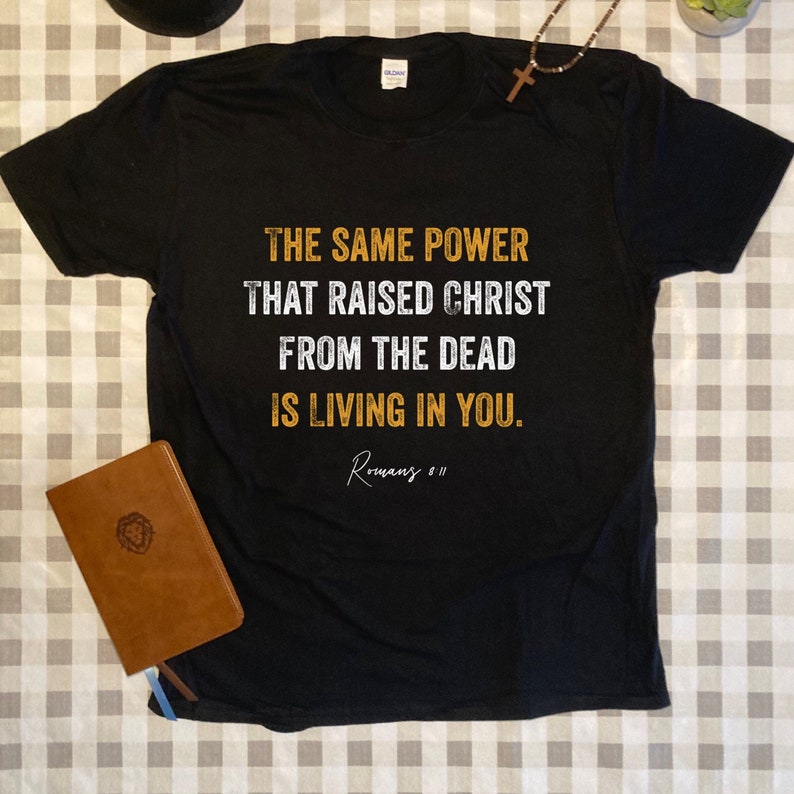 May include: Black t-shirt with a white graphic that reads "THE SAME POWER THAT RAISED CHRIST FROM THE DEAD IS LIVING IN YOU. Romans 8:11"