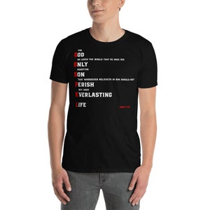May include: Black t-shirt with white text that reads "For God So Loved The World That He Gave His Only Begotten Son That Whosoever Believeth In Him Should Not Perish But Have Everlasting Life John 3:16".