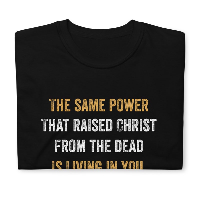 May include: Black t-shirt with the text "THE SAME POWER THAT RAISED CHRIST FROM THE DEAD IS LIVING IN YOU" in yellow.