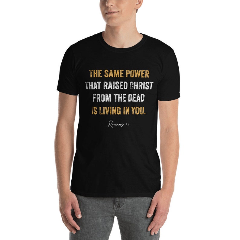 May include: Black t-shirt with a white and gold graphic print that reads "THE SAME POWER THAT RAISED CHRIST FROM THE DEAD IS LIVING IN YOU. Romans 8:11"