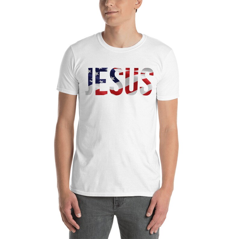 May include: White t-shirt with the word "JESUS" printed in red, white, and blue, resembling the American flag.