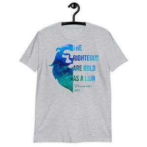 Pode incluir: Uma camiseta cinza com um design de le&atilde;o aquarela azul e verde. O texto "The Righteous Are Bold As A Lion Proverbs 28:1" est&aacute; impresso na camiseta.