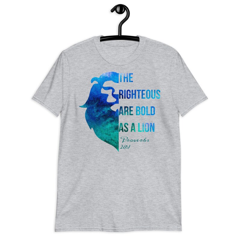 Pode incluir: Uma camiseta cinza com um design de le&atilde;o aquarela azul e verde. O texto "The Righteous Are Bold As A Lion Proverbs 28:1" est&aacute; impresso na camiseta.