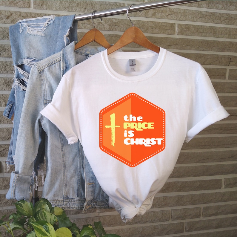 Peut inclure: T-shirt blanc avec un graphique d'une croix et le texte "the price is christ" dans un hexagone orange avec du texte jaune.