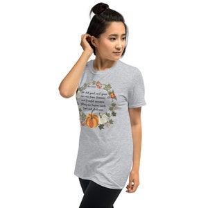 Puede incluir: Una camiseta gris jaspeada de manga corta con un dise&ntilde;o de corona de follaje de oto&ntilde;o y calabazas. El texto "He did good, and gave us rain from heaven, and fruitful seasons, filling our hearts with food and gladness" est&aacute; impreso en la camiseta.