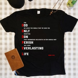 May include: Black t-shirt with white text that reads "For God So Loved The World That He Gave His Only Begotten Son That Whosoever Believeth In Him Should Not Perish But Have Everlasting Life" and "John 3:16".