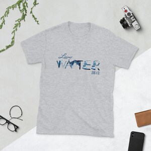 May include: A heather grey t-shirt with a blue and white graphic design that says "Living Water" with the scripture reference "John 4:10" underneath.