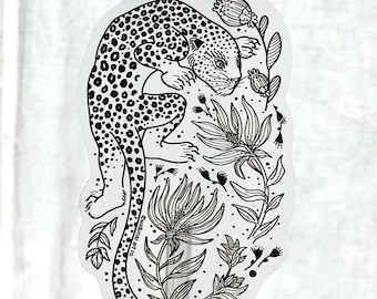 Puede incluir: Pegatina en blanco y negro de arte de línea de un leopardo con un pelaje manchado, rodeado de flores y hojas estilizadas. La pegatina tiene el texto "Ecolier Art Co." en la parte inferior.