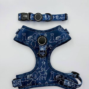 Op de afbeelding: Een marineblauwe hondentuig en bijpassende halsbandset. De set heeft een wit lijntekeningpatroon van verschillende hondenrassen. De halsband heeft een zwarte gesp en het tuig heeft verstelbare bandjes en een zwarte sluiting.